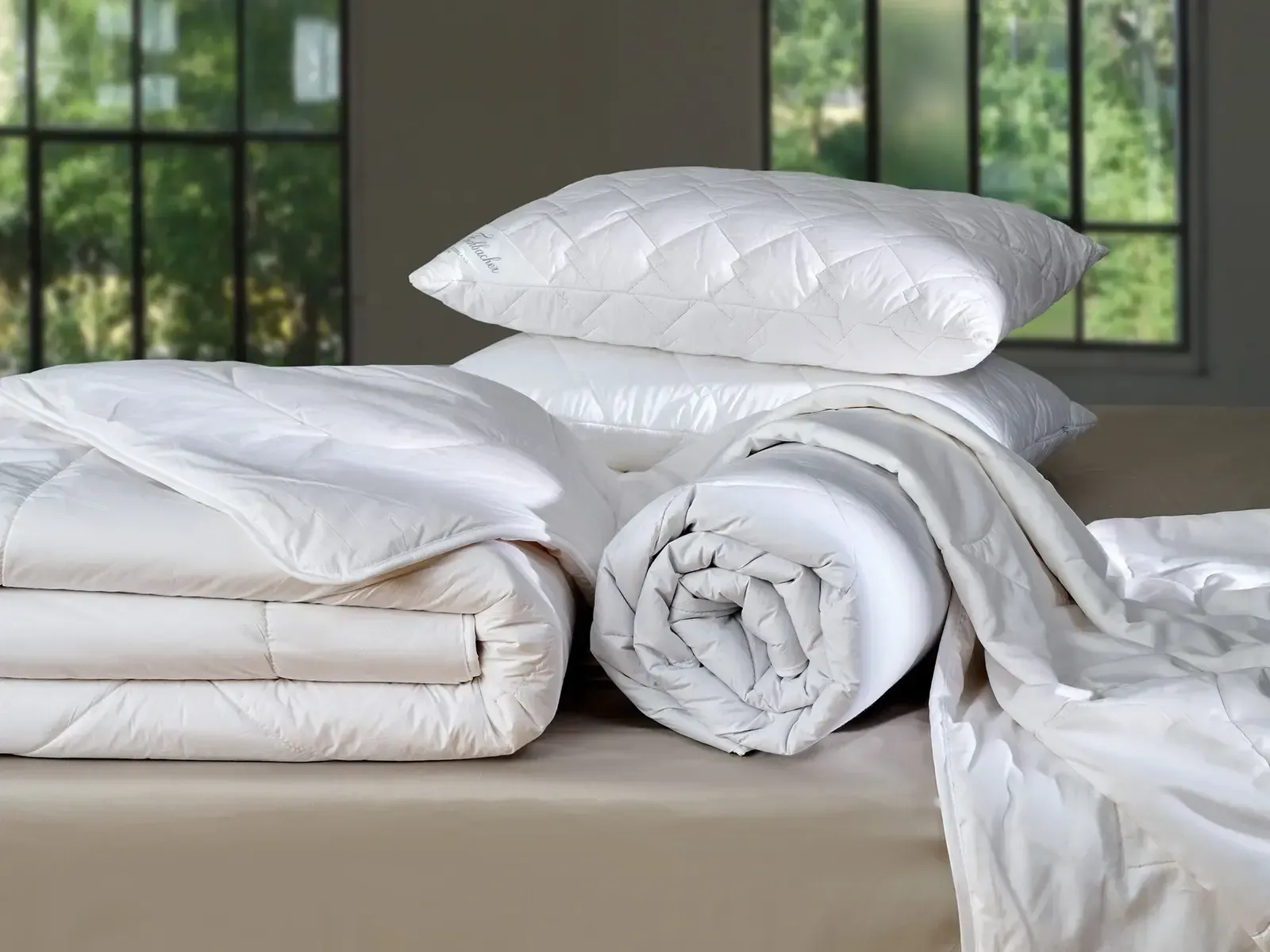 Ein Stapel weißer Decken und Kissen auf einem Bett