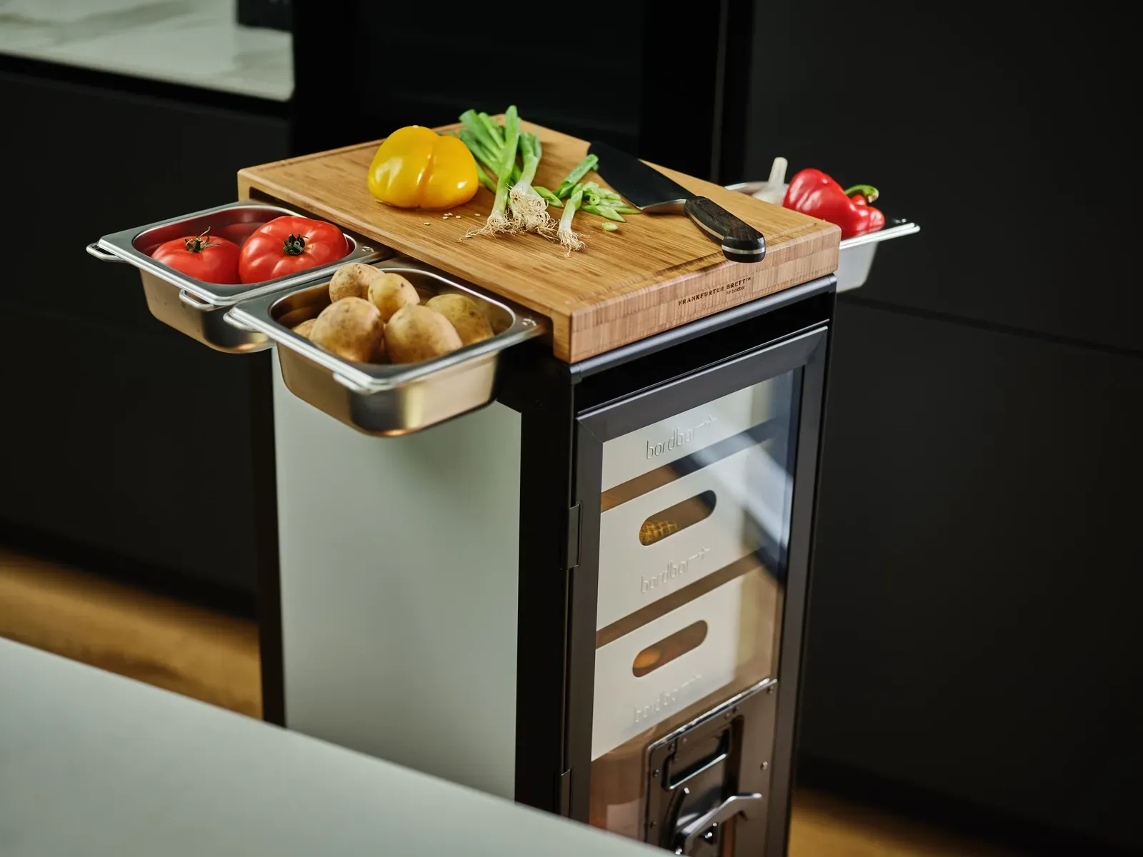 Auf einer Küchentheke liegt ein Schneidebrett mit Gemüse darauf.