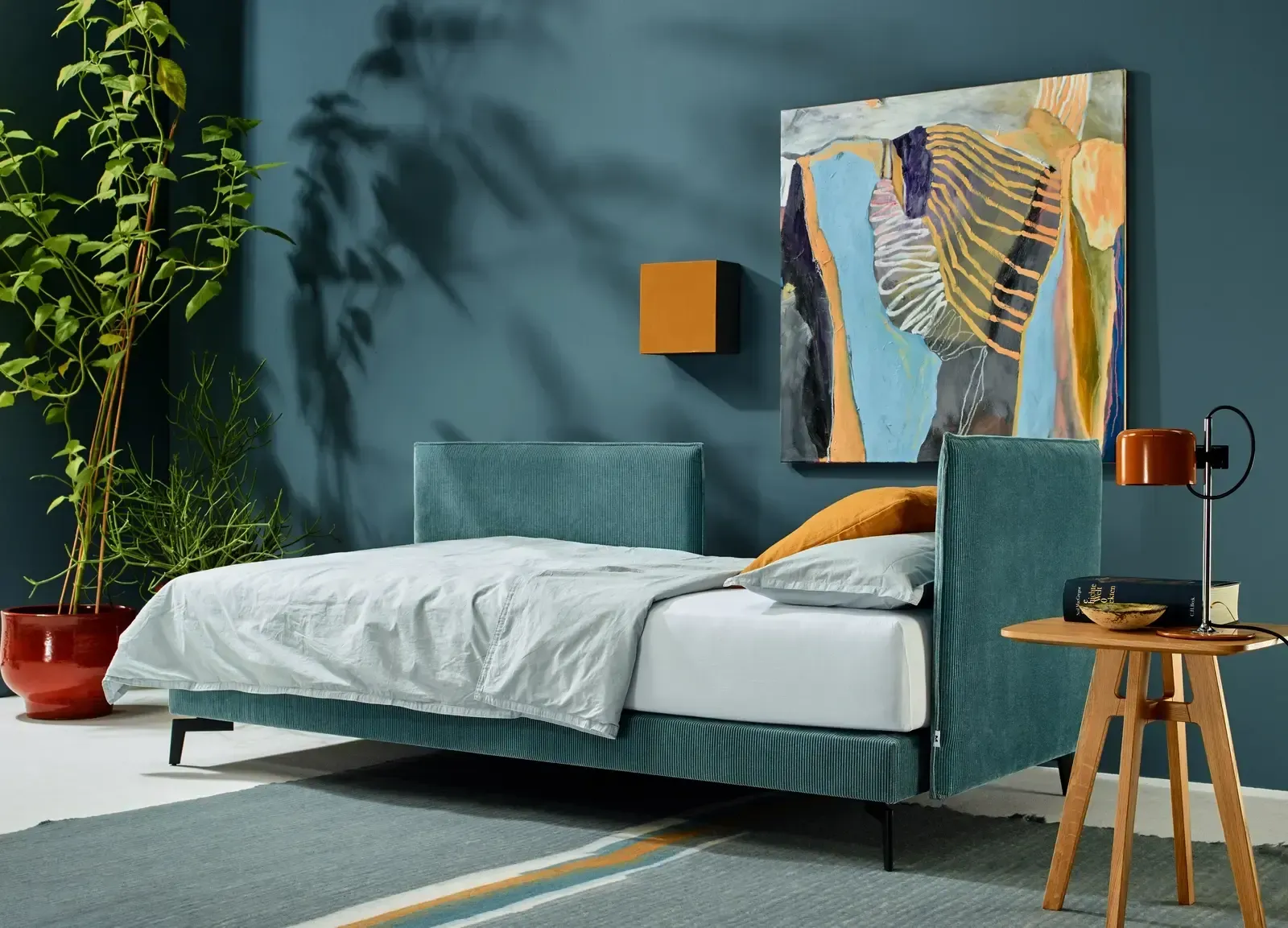 Ein Wohnzimmer mit einem blauen Sofa und einem Gemälde an der Wand.