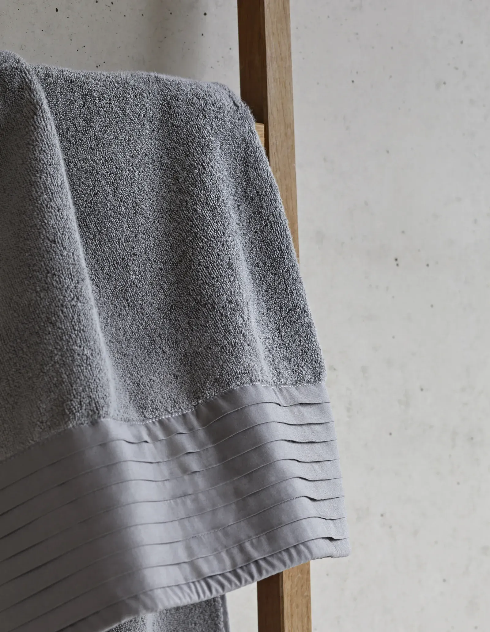 Ein graues Handtuch hängt an einem Holzständer.