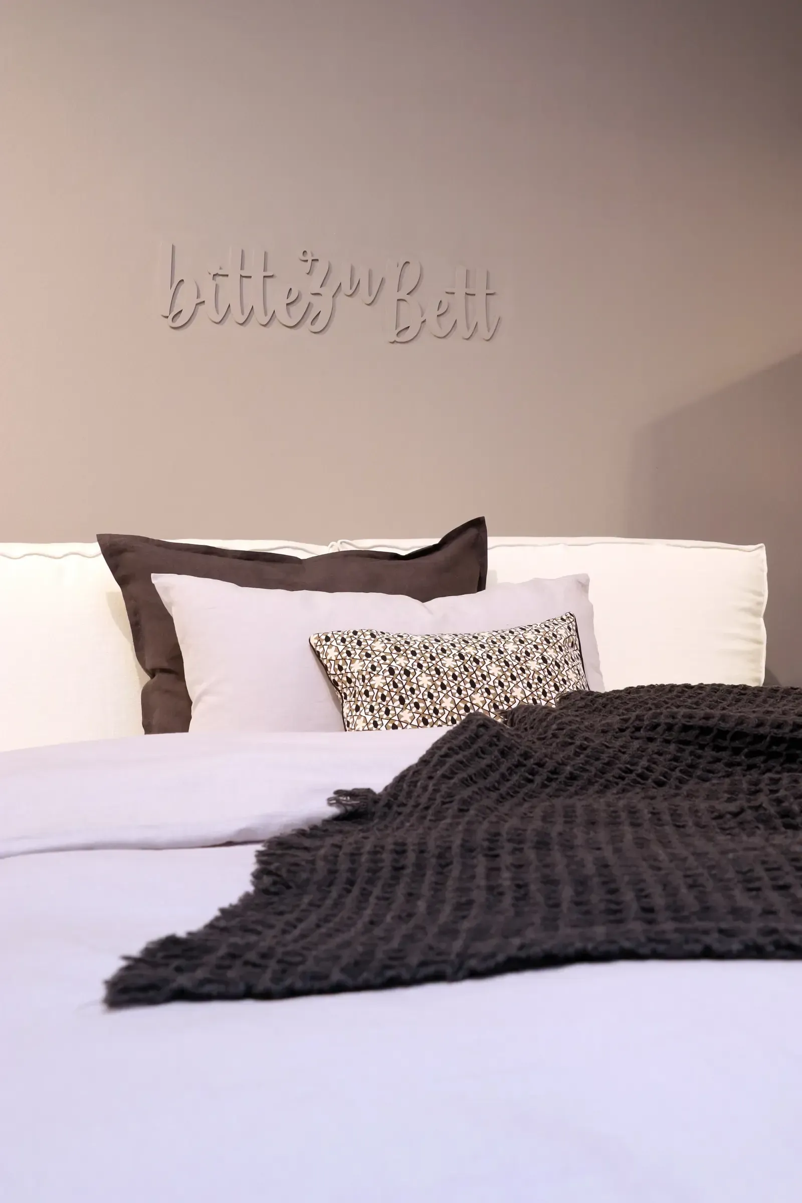 Ein Bett mit Kissen und einer Decke darauf.