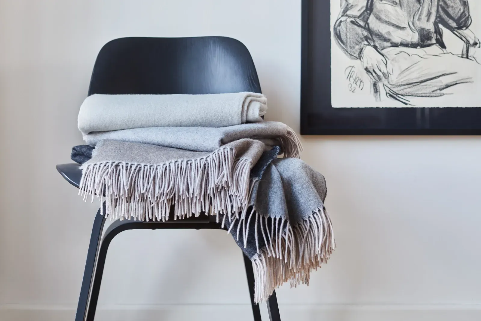 Ein Stuhl mit einer Decke darauf und einem Bild an der Wand dahinter.