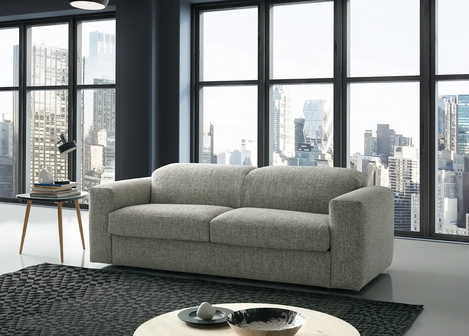 Ein Wohnzimmer mit Couch, Couchtisch und großen Fenstern.