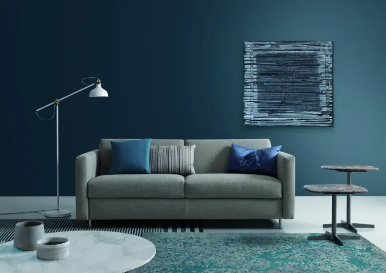 Ein Wohnzimmer mit Couch, Tisch, Lampe und Gemälde an der Wand.