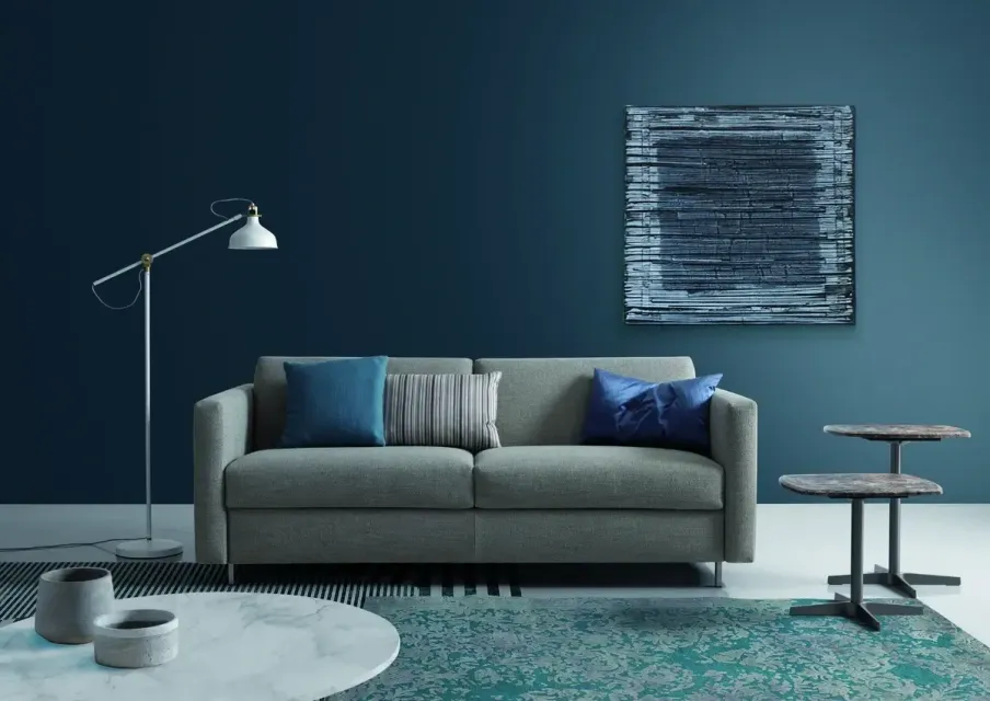 Ein Wohnzimmer mit Couch, Tisch, Lampe und Gemälde an der Wand.