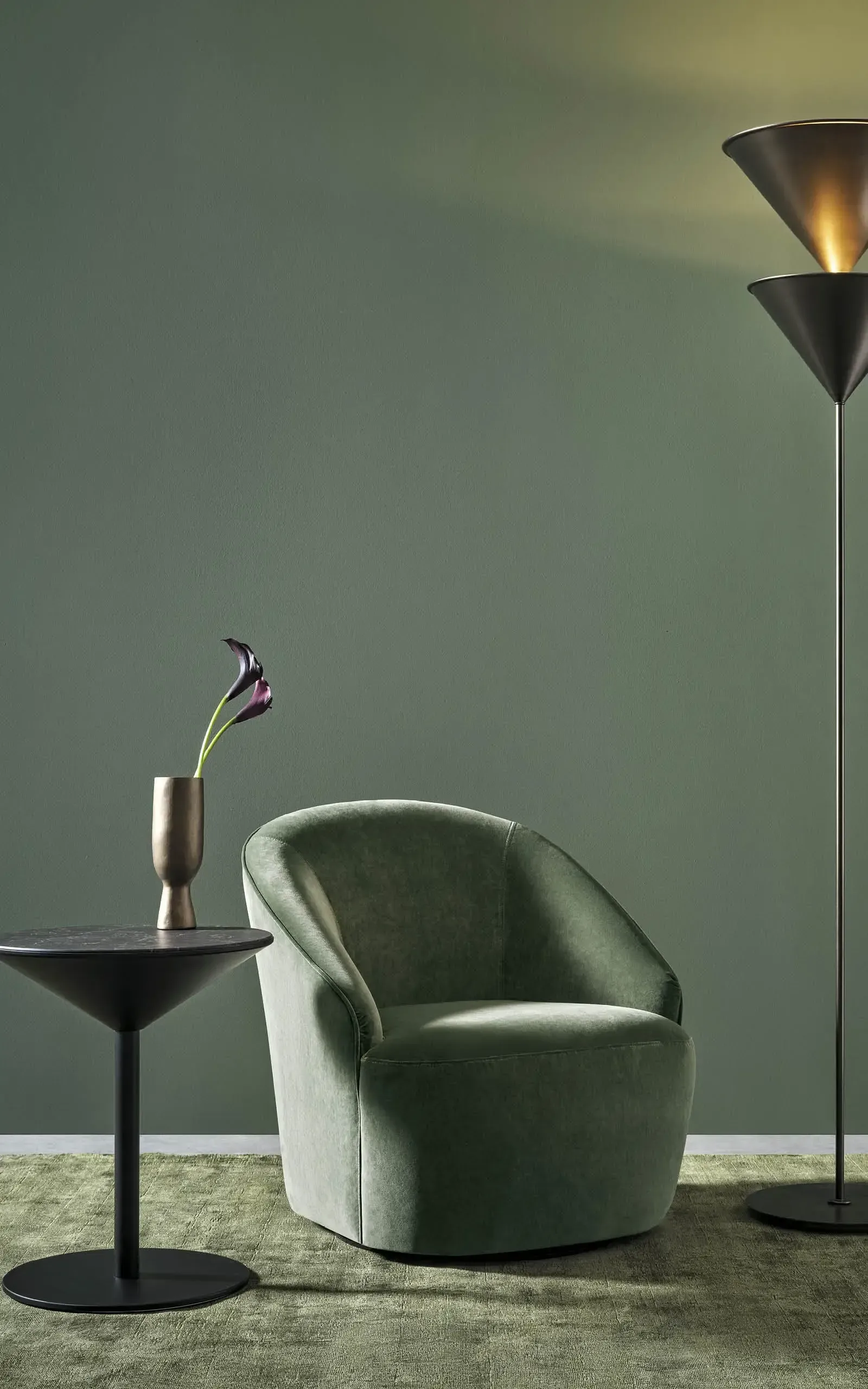 Ein grüner Stuhl steht neben einem Tisch mit einer Vase mit Blumen darauf.