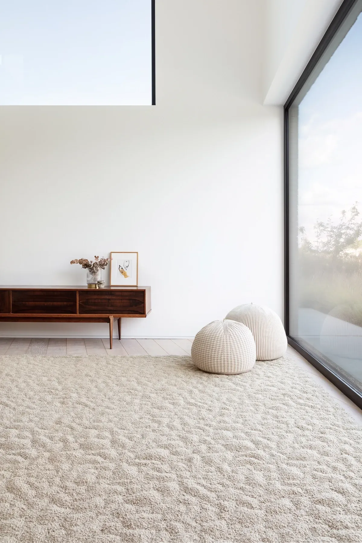 Ein Wohnzimmer mit einem großen Fenster und einem Teppich auf dem Boden.