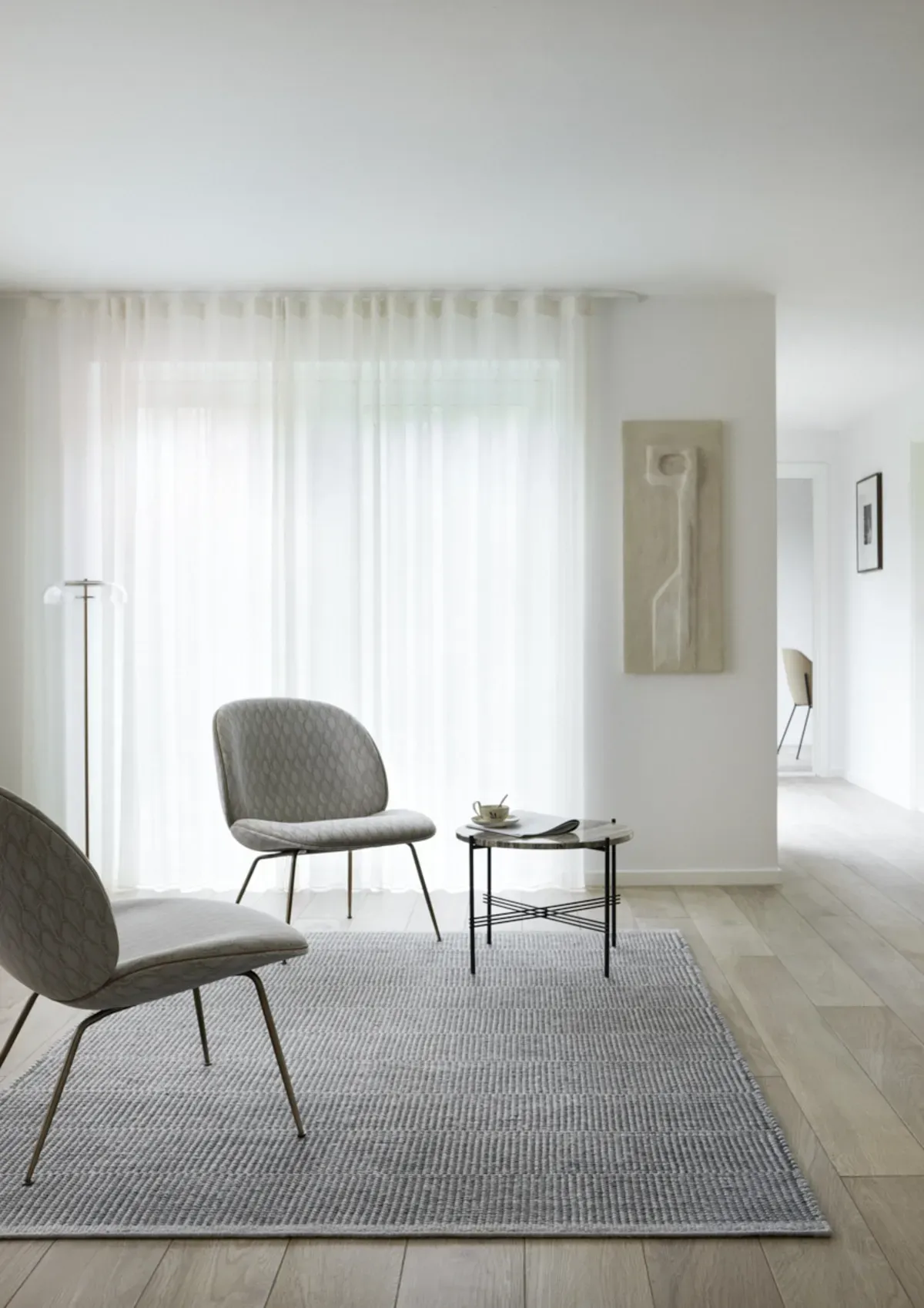 Ein Wohnzimmer mit zwei Stühlen, einem Tisch und einem Teppich.