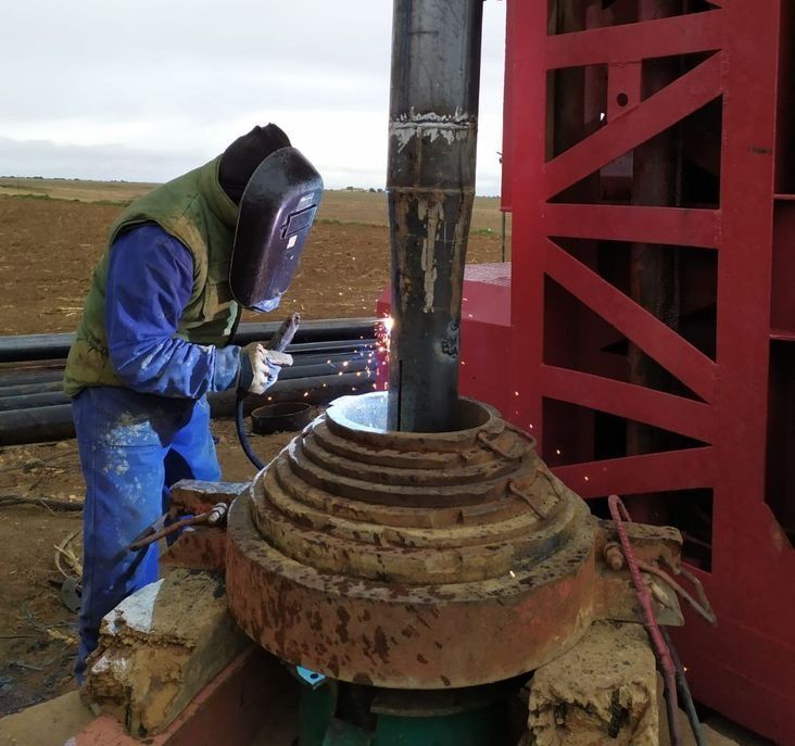 Un hombre que lleva una máscara de soldar está trabajando en una pieza de metal.