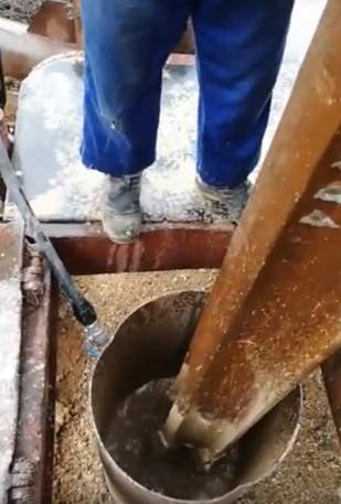 Una persona está mezclando hormigón en un balde con una pala.