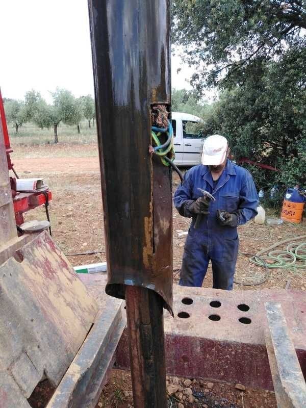 Un hombre con un mono azul está trabajando en una tubería de metal.