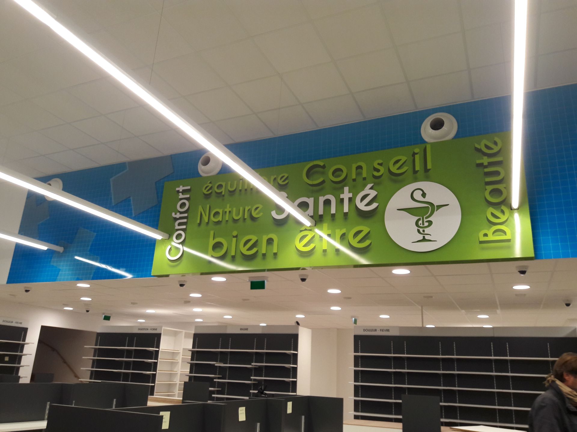 A pharmacy interior with a green sign reading 
