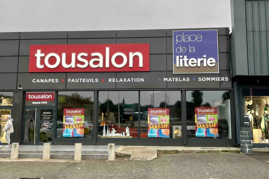 Une façade pour Tousalons et place de la literie, vendant des canapés, des chaises et de la literie, avec de grandes vitrines.