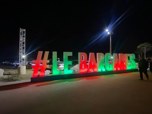 Une grande enseigne lumineuse affichant #LE BARGANES en lettres rouges et vertes, se détachant sur un fond de nuit sombre en extérieur.