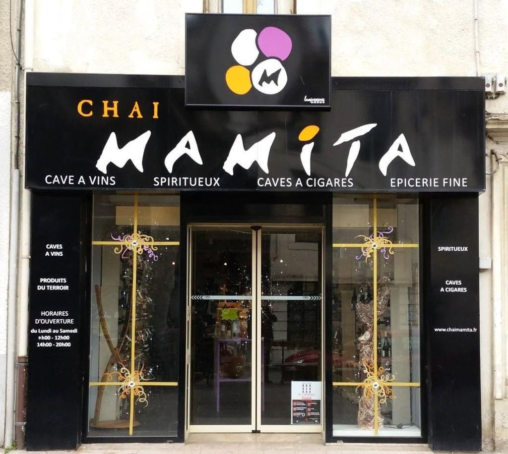 Façade de Chai Mamita, un magasin de vins, spiritueux, cigares et produits gastronomiques avec une façade noire et une enseigne dorée.
