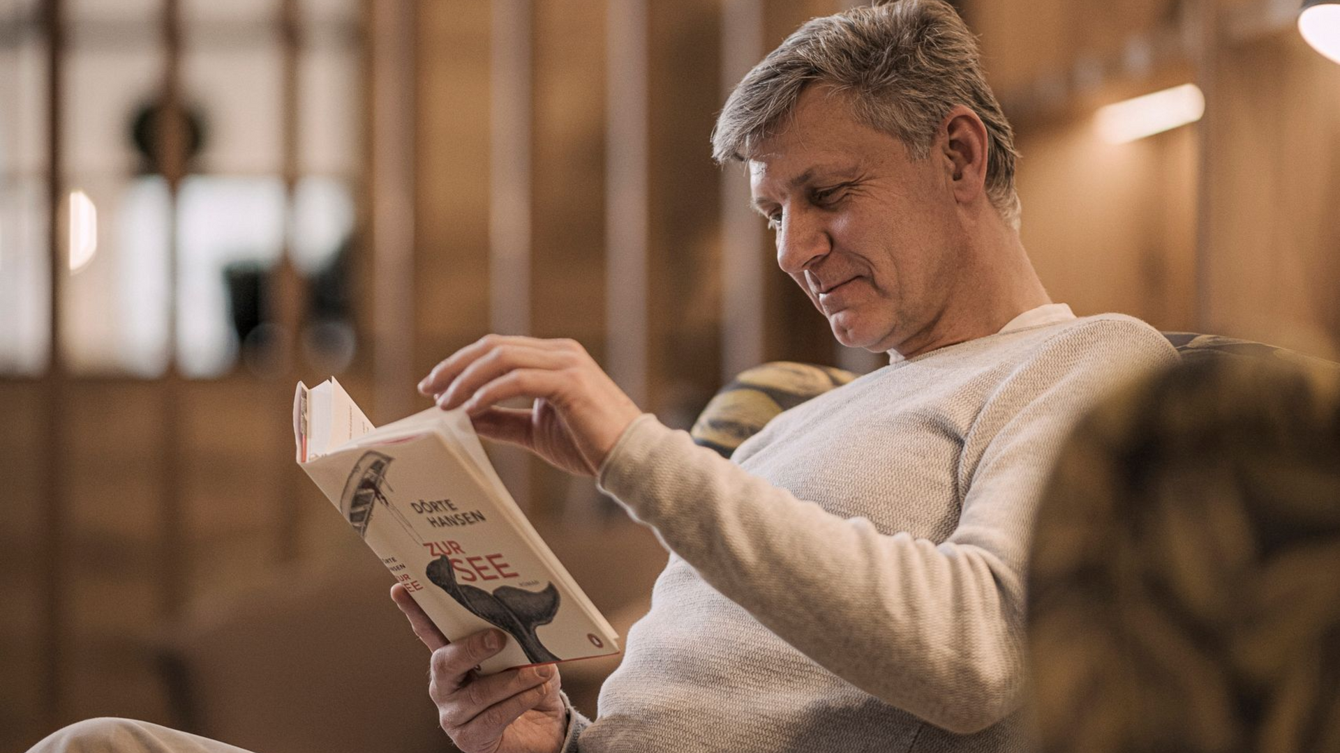 Ein Mann liest ein Buch im Aufenthaltsbereich des MY MAYR MED Resorts.