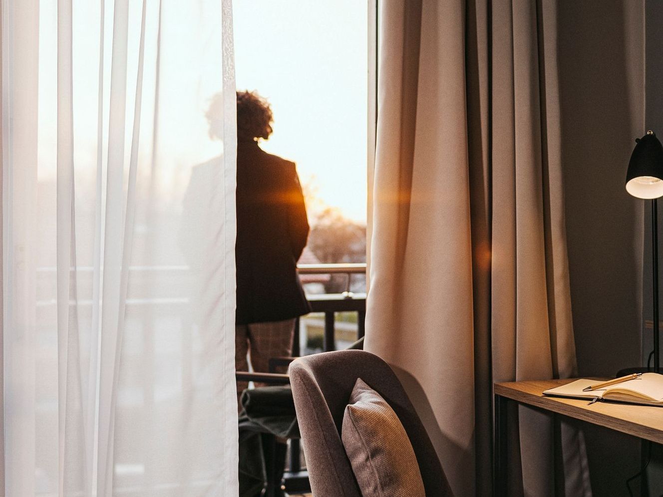 Ein Gast genießt die Sonne auf dem Balkon eines MY MAYR Basic Zimmers.