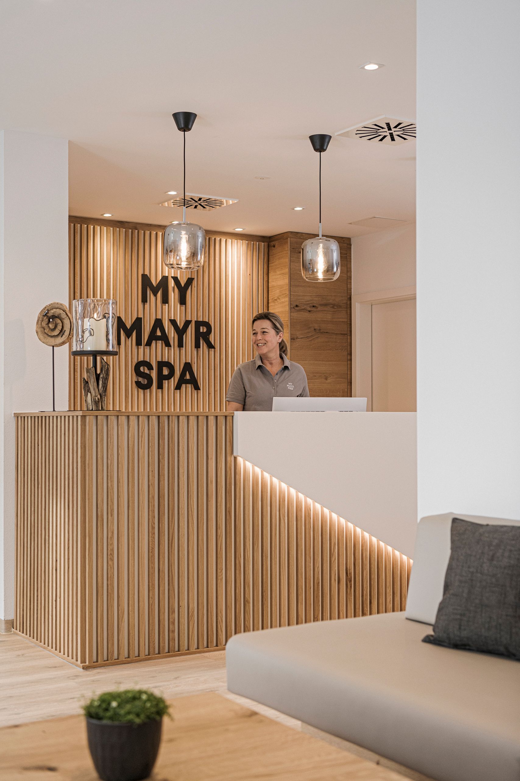 Eine Rezeptionistin begrüßt einen Gast im MY MAYR SPA Bereich.