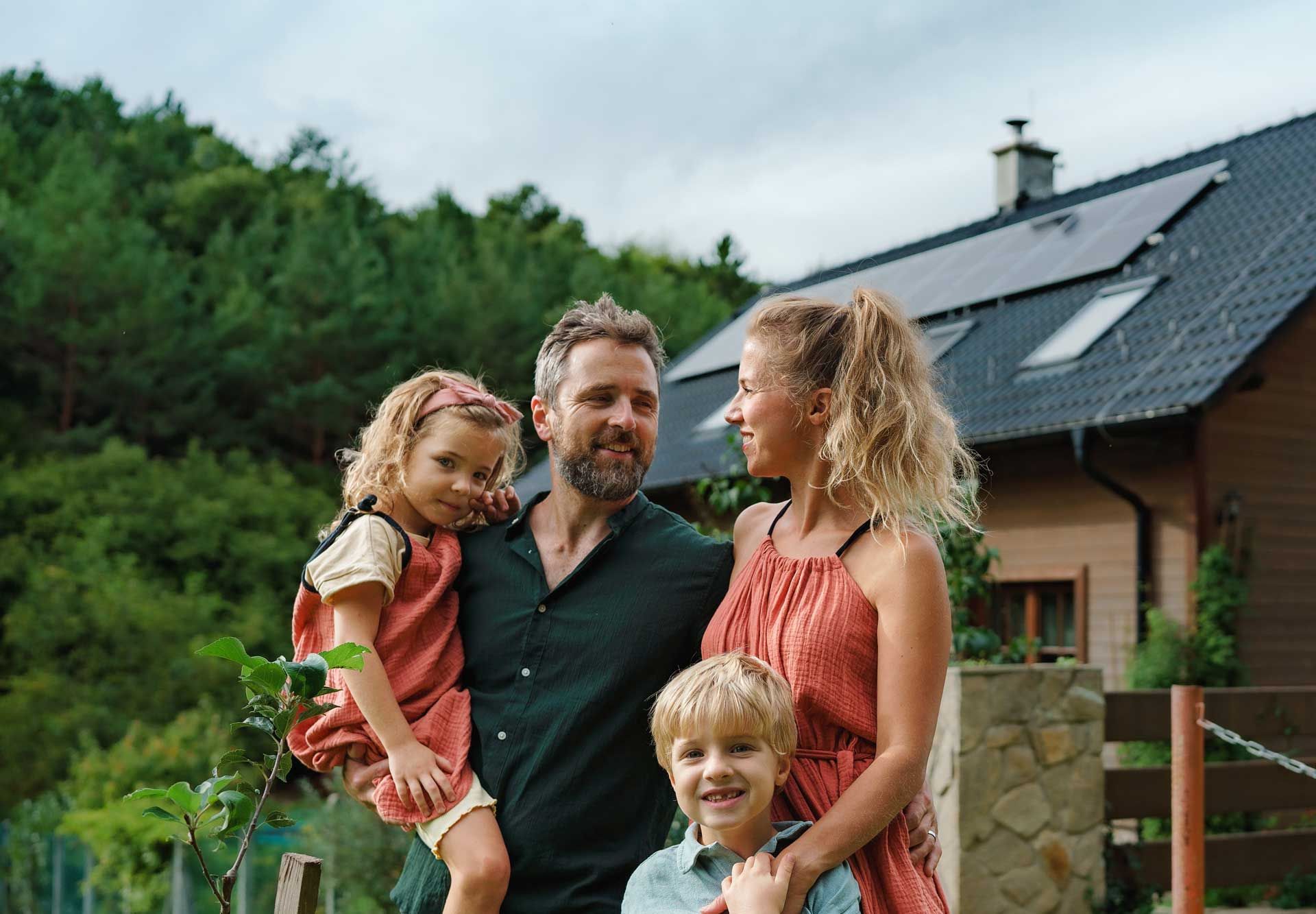 Une famille posant devant une maison équipée de panneaux solaires