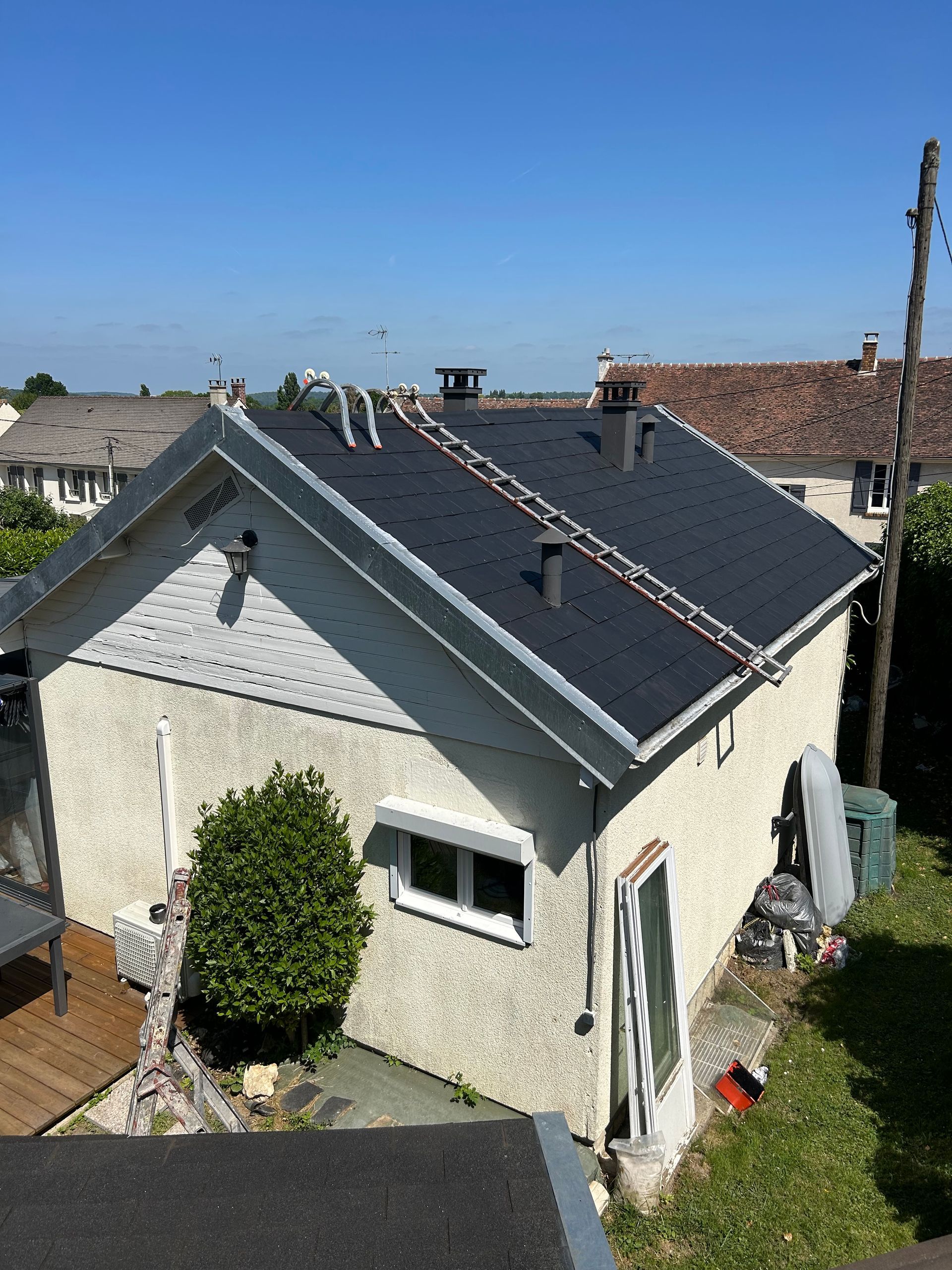 Échelles placées sur les deux pans d'un toit couvert en ardoises fraichement nettoyé