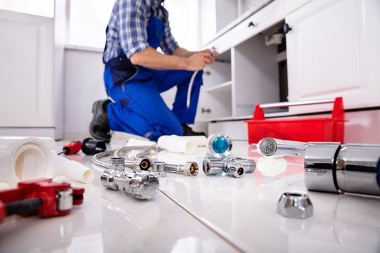 Un fontanero está arreglando un fregadero en una cocina.