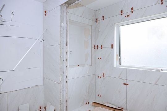 Un baño en construcción con azulejos blancos y una ventana.