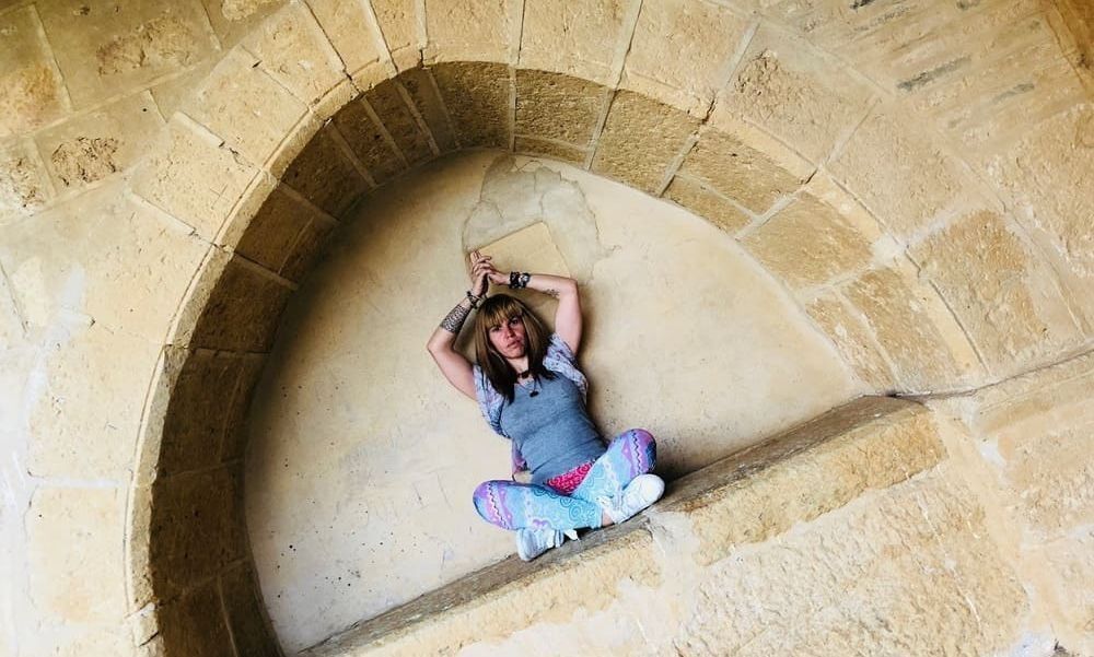 Una mujer está sentada en un arco de piedra.