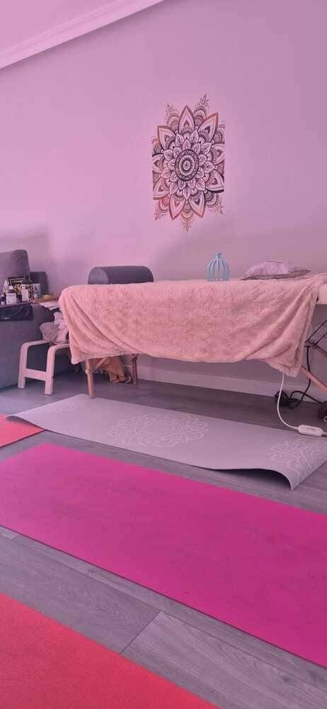 Una habitación con una mesa de masajes y una esterilla de yoga en el suelo.
