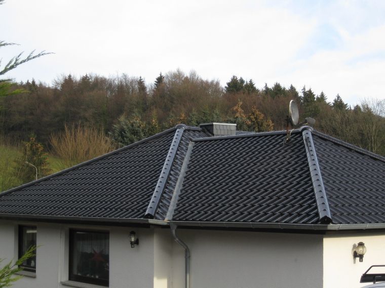Ein weißes Haus mit einem schwarzen Dach und einer Satellitenschüssel darauf