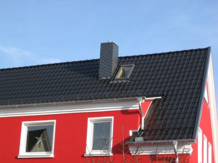 Ein rotes Haus mit einem schwarzen Dach und einem Oberlicht