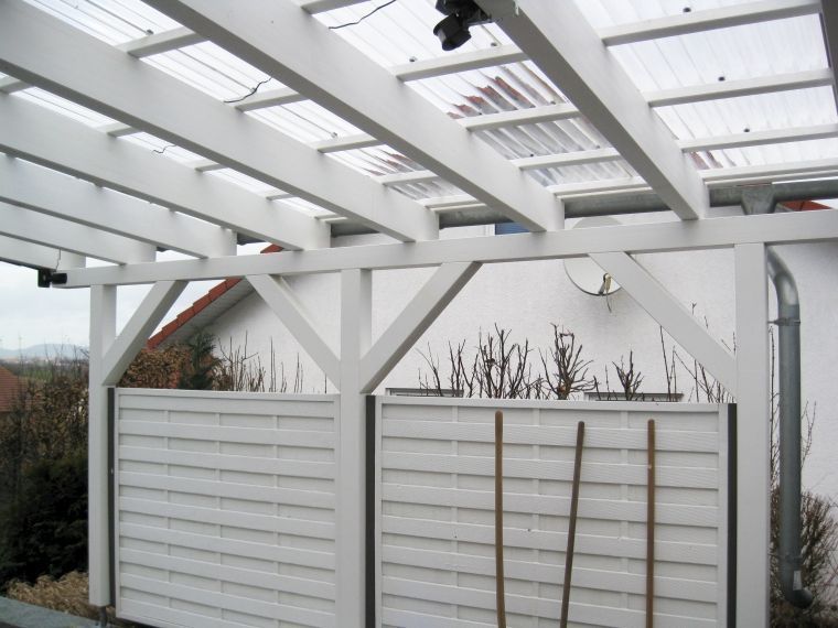 Eine weiße Pergola mit einem durchsichtigen Dach und einem weißen Zaun