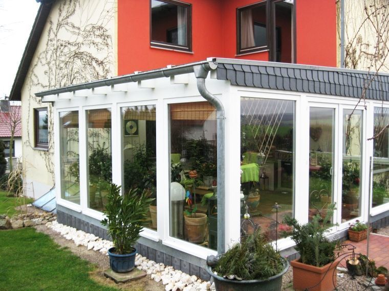 Ein rotes Haus mit einer weißen Veranda mit vielen Fenstern
