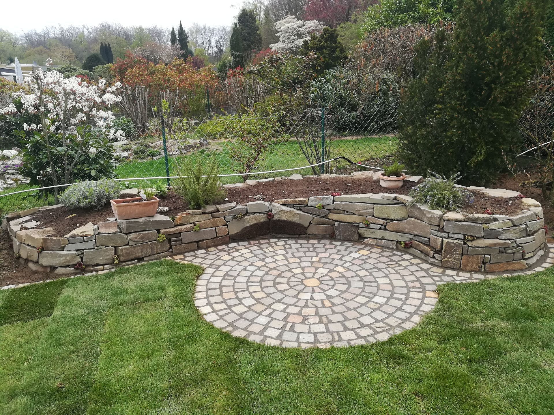 Eine Steinmauer mit einem runden Innenhof in der Mitte in einem Garten. Foto von Dennis Schoo Gartenideen & Gestaltung
