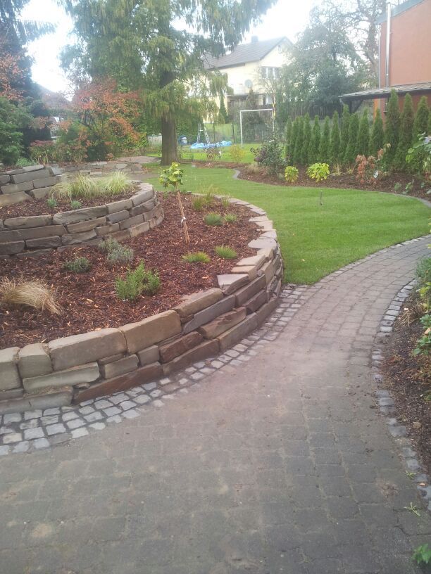 Ein gemauerter Gehweg führt zu einem üppigen grünen Garten. Foto von Dennis Schoo Gartenideen & Gestaltung