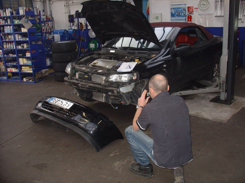 Ein Mann, der ein Foto von einem Auto mit geöffneter Motorhaube macht