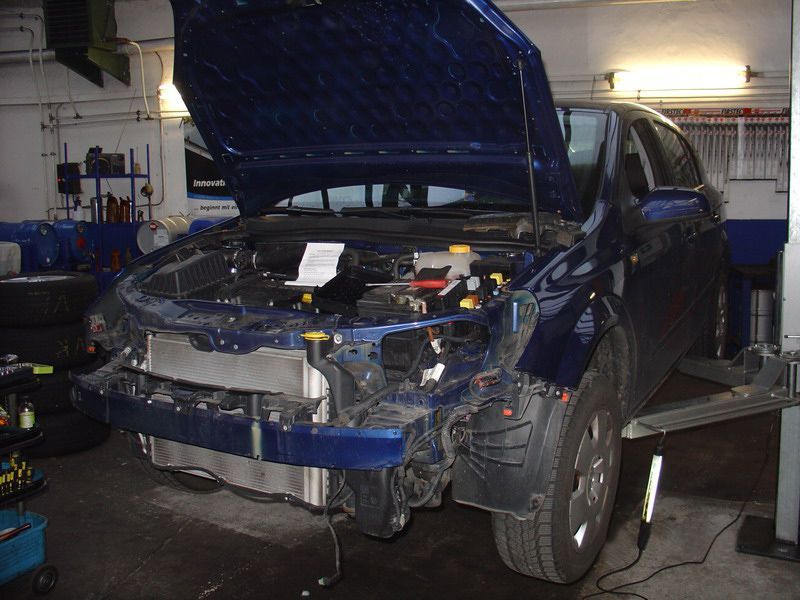 Ein blaues Auto mit offener Motorhaube in einer Garage