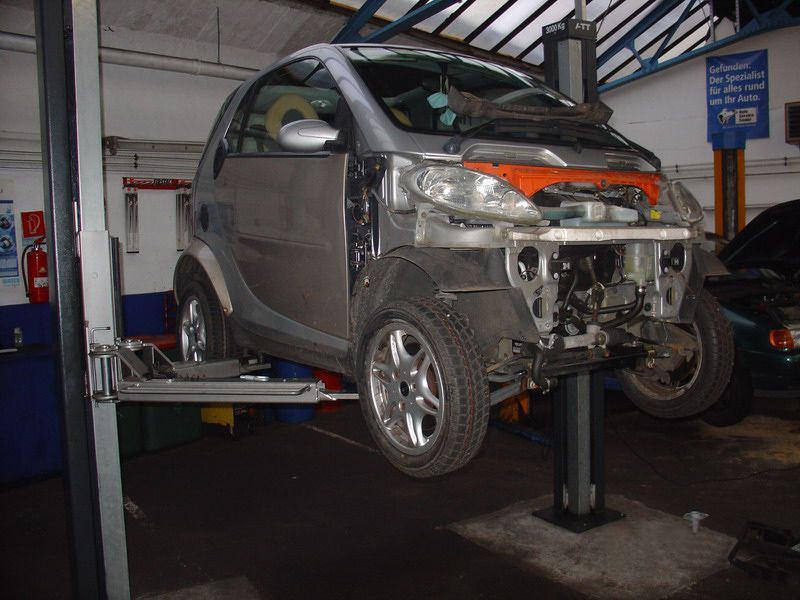 Ein Smart steht auf einer Hebebühne in einer Garage
