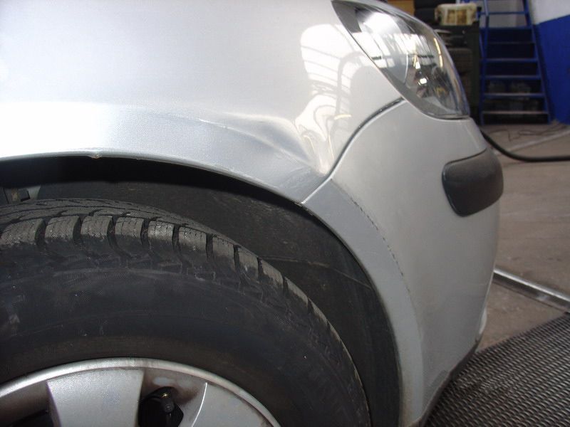 Ein silbernes Auto mit schwarzen Reifen steht in einer Garage