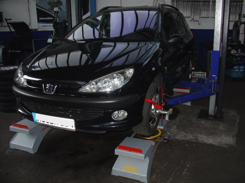 Ein schwarzes Auto steht auf einer Hebebühne in einer Garage