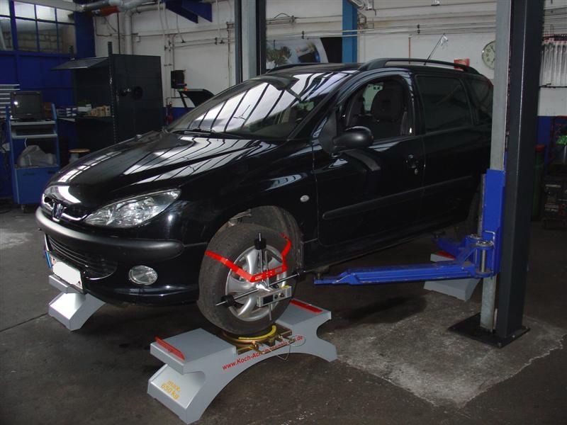 Ein schwarzes Auto steht auf einer Hebebühne in einer Garage