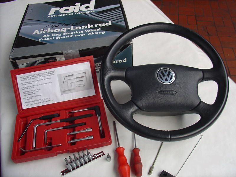 Ein schwarzes Lenkrad sitzt neben einer Box mit der Aufschrift Raid