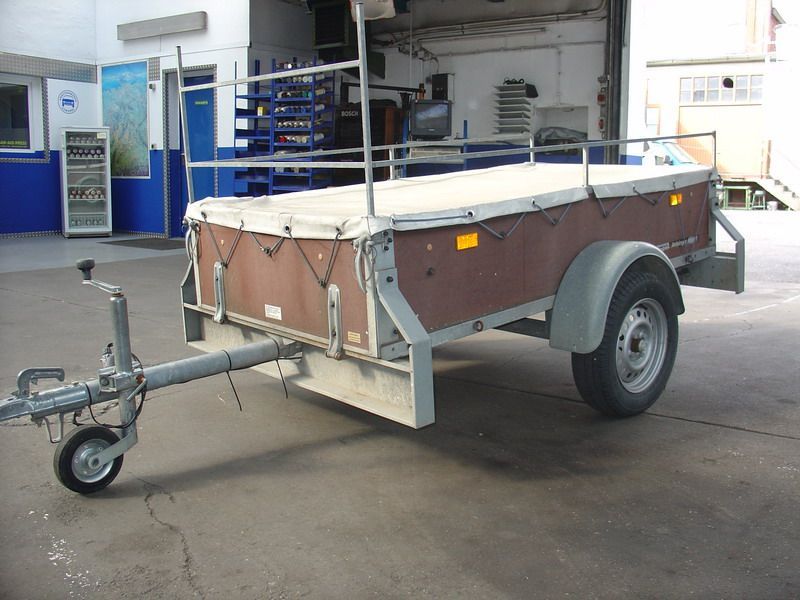 Ein kleiner Anhänger steht auf einem Parkplatz