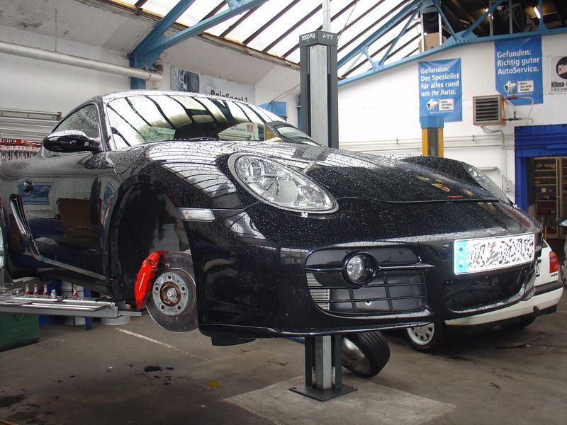 Ein schwarzer Sportwagen steht auf einer Hebebühne in einer Garage