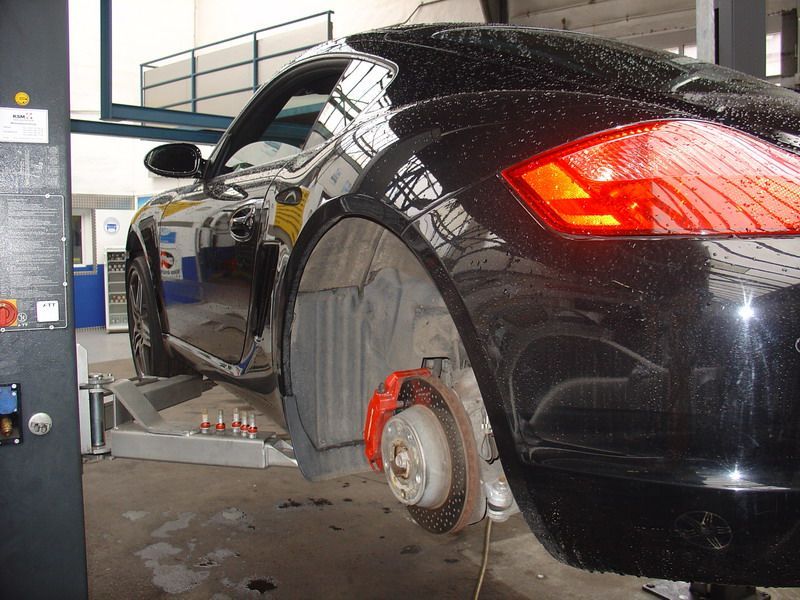 Ein schwarzes Auto mit roten Bremssätteln steht auf einer Hebebühne