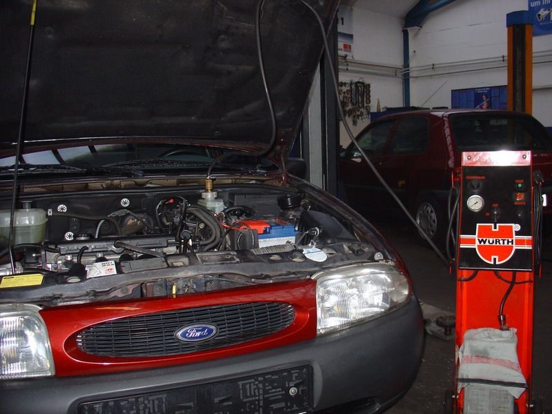 Ein roter Ford mit geöffneter Motorhaube in einer Garage