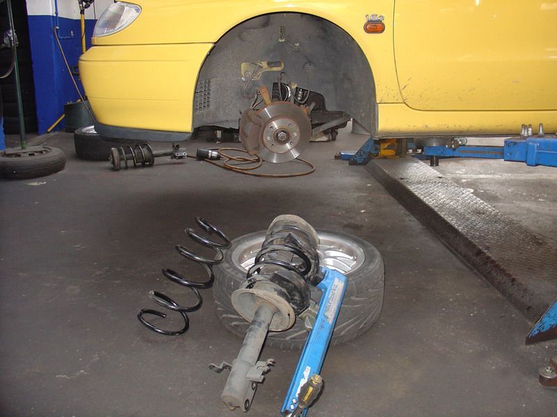 In einer Garage wird an einem gelben Auto gearbeitet