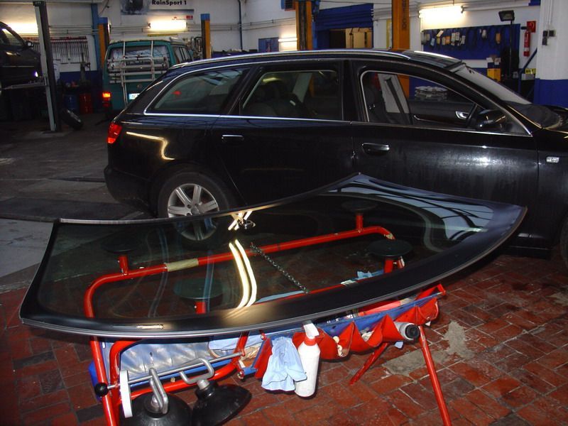 Ein schwarzes Auto in einer Garage mit einer Windschutzscheibe auf einem Ständer