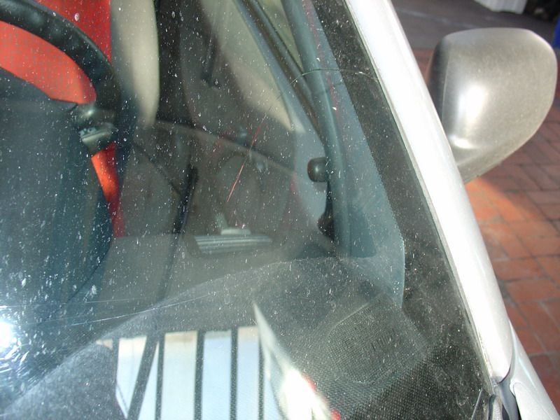 Eine Nahaufnahme einer Windschutzscheibe eines Autos mit einem Lenkrad im Hintergrund