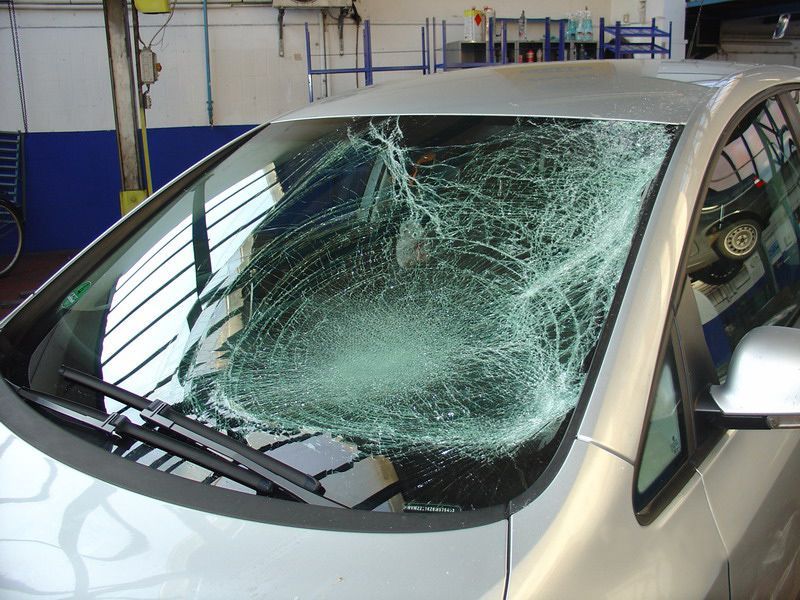 Ein silbernes Auto mit einer kaputten Windschutzscheibe in einer Garage