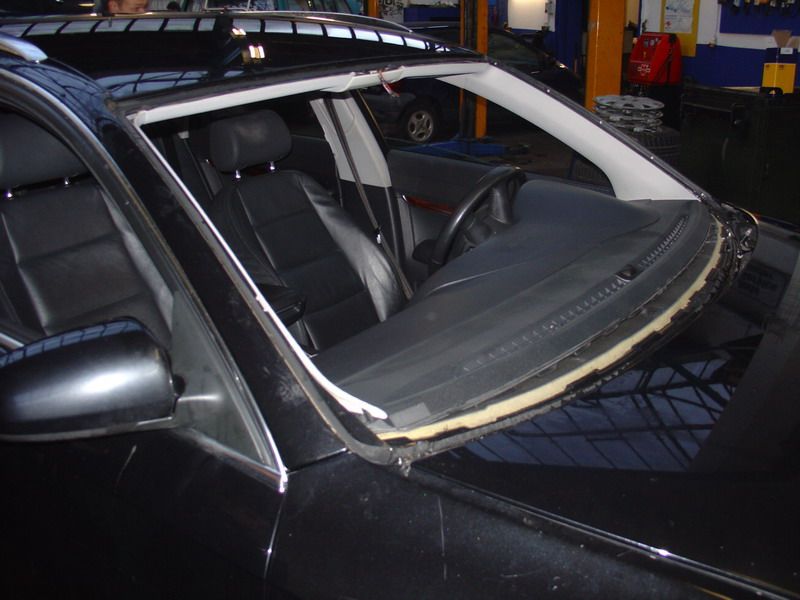 Ein schwarzes Auto mit einer kaputten Windschutzscheibe in einer Garage